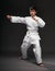 A teenager dressed in martial arts clothing poses on a dark gray background, a sports concept