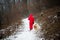 teenager dressed in red winter color walks in snowy path in the