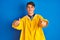 Teenager fisherman boy wearing yellow raincoat over  background approving doing positive gesture with hand, thumbs up