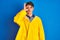 Teenager fisherman boy wearing yellow raincoat over  background doing ok gesture with hand smiling, eye looking through