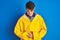 Teenager fisherman boy wearing yellow raincoat over  background with hand on stomach because indigestion, painful illness