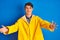 Teenager fisherman boy wearing yellow raincoat over  background looking at the camera smiling with open arms for hug