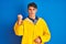 Teenager fisherman boy wearing yellow raincoat over isolated background angry and mad raising fist frustrated and furious while