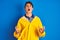 Teenager fisherman boy wearing yellow raincoat over isolated background crazy and mad shouting and yelling with aggressive