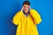 Teenager fisherman boy wearing yellow raincoat over isolated background with hand on head for pain in head because stress