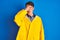 Teenager fisherman boy wearing yellow raincoat over isolated background peeking in shock covering face and eyes with hand, looking