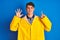Teenager fisherman boy wearing yellow raincoat over isolated background showing and pointing up with fingers number six while