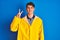 Teenager fisherman boy wearing yellow raincoat over isolated background showing and pointing up with fingers number two while