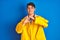 Teenager fisherman boy wearing yellow raincoat over isolated background smiling in love doing heart symbol shape with hands