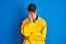 Teenager fisherman boy wearing yellow raincoat over isolated background thinking looking tired and bored with depression problems