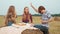 Teenager friends eating pizza on hay stack on harvesting field. Young girls and boy eating pizza on rural picnic at