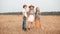 Teenager friends standing on countryside field on haystack background. Boy and two girls posing on harvesting field in