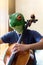 Teenager with frog mask playing cello showing detail