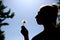 The teenager gently blows and spreads the dandelion seeds against the blue sky.