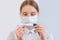 Teenager girl of 12-15 years old, in protective medical mask covers her face, holds a digital thermometer in her hands