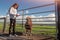 Teenager girl with a bag of snack and beautiful brown pony behind metal fence. Scene at open farm or zoo. Active learning nature