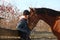 Teenager girl and bay horse hugging each other