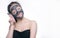 Teenager girl in a black mask, natural photo of a real mask on a young girl. Texture dark cream. Model on a white background