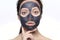 Teenager girl in a black mask, natural photo of a real mask on a young girl. Texture dark cream. Model on a white background