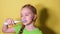 Teenager girl brushes her teeth on yellow background. Child girl in green t-shirt uses an electric toothbrush