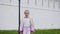 Teenager girl in colorful clothes going to camera on white wall background. Young fashion model posing and walking front