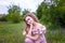 Teenager girl with curly long hair in pink costume holding field flower. Springtime blossoming and tender youth