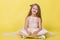 Teenager girl in a dress on a yellow background posing for the camera and sits on the floor