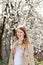 Teenager girl with flowering branch of an apricot tree in a spring blooming garden enjoying warm sunny weather, serene people and