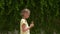 Teenager girl with ice cream walking on background wall with green plant