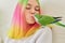 Teenager girl kissing a parrot. Close-up face of woman and green quaker parrot