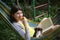 Teenager girl lay in hammock with book,kitten and apricot