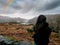 Teenager girl looking at rainbow over magnificent valley in a mountains and dark dramatic sky. Ladies view, Killarney, Ireland,