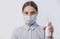 Teenager girl in medical mask, antiseptic spray bottle, focus on eyes, prevention of virus infection safety, carefully