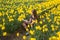 Teenager girl paints flowers, sitting in blooming field.
