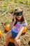 Teenager girl and pumpkin in the vegetable garden. A girl with a pumpkin wearing glasses for Halloween