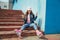 Teenager girl on roller skates sitting on step in city
