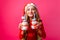 teenager girl in Santa hat and tinsel on the neck, holds 2 bottles of juice Christmas in the shape of a snowman on a red