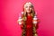 teenager girl in Santa hat and tinsel on the neck, holds 2 bottles of juice Christmas in the shape of a snowman on a red