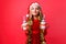 Teenager girl in Santa hat and tinsel on the neck, holds 2 bottles of juice Christmas in the shape of a snowman on a red