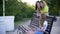 Teenager girl sitting on bench using phone and two woman behind in summer park. Two woman and teen girl walking in