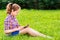 Teenager girl sitting on the grass with digital tablet on her knees