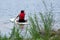 A teenager girl sitting on a paddle board.