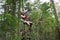 Teenager girl sliding on a flying fox zip line during a treetop adventure climbing