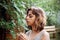 Teenager Girl sniffing chamomile flower in the forest. Natural beauty. Candid moments