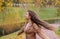 A teenager girl is spinning under foliage of a birch in the autumn park