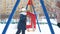 Teenager girl swinging on snowy playground at holiday vacations in winter city. Happy girl friends swinging on swing on