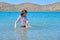 Teenager girl is touching, enjoying sea water in the bay