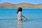 Teenager girl is touching, enjoying sea water in the bay, back view