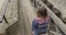 Teenager girl walking across vintage wooden bridge in old tourist town, back view