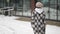 Teenager girl is walking at winter day in city, wearing coat and knitted hat